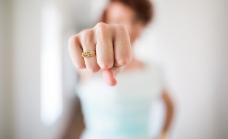 woman with fist out in front showing ring with 'mantra' style statement on it