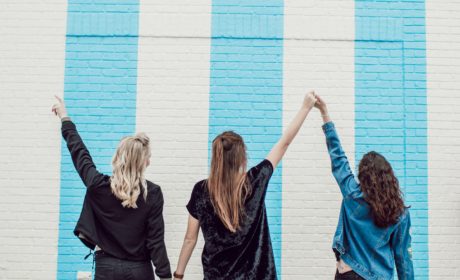 three women with linked arms up in victory pose to show the strength of women's networks