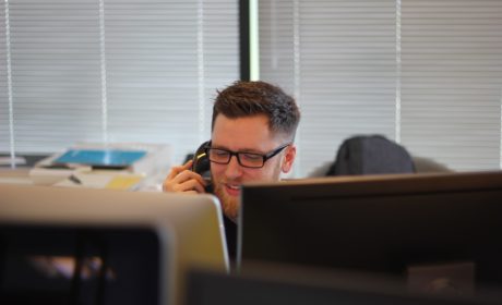 person on phone smiling above computer screen