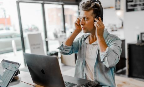 person with headphones in front of laptop